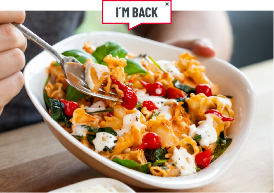 Eine Person hällt eine Schale mit der Pasta in die Kamera.